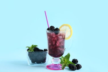 Lezzetli böğürtlenli limonata ve mavi arka planda malzemeler.