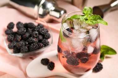 Lezzetli böğürtlenli limonata ve arka plan olarak pembe peçeteli sıva podyumu, yakın plan.