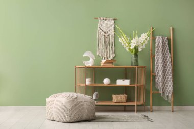 Rafa kaldırma ünitesi, puf ve vazo içinde güzel beyaz gladiolus çiçekleri oturma odasının iç tarafındaki yeşil duvarın yanında.