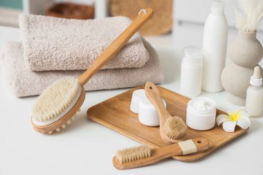Tahta tahta, masaj vücut fırçaları, şişeler ve kozmetik ürünler odada, yakın plan.