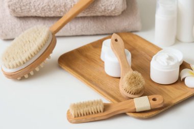 Tahta tahta, masaj vücut fırçaları ve kozmetik ürünler odadaki masada, yakın plan.