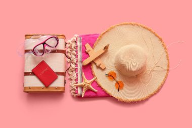Klasik bavul, pasaport, yüzme maskesi ve pembe arka planda plaj aksesuarları olan kompozisyon