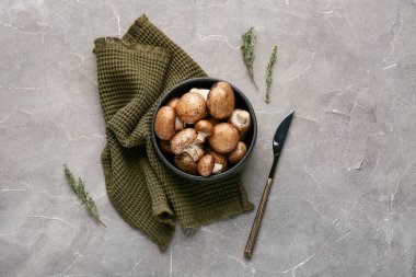 Gri grunge arka planda ham şampiyon mantarlı siyah kase, yakın plan.