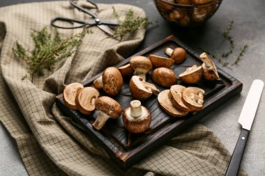 Arka planda çiğ şampiyon mantarlı tahta kesme, yakın plan.