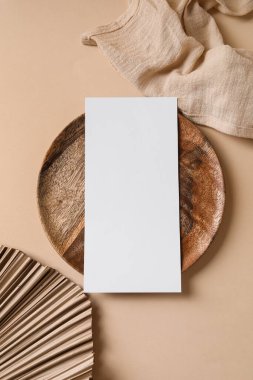 Boş kart, tepsi, tropikal yaprak ve bej arka planda peçete içeren kompozisyon, yakın plan