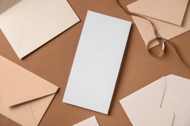 Kahverengi zemin üzerinde boş kart, zarf ve kurdele olan kompozisyon, yakın plan