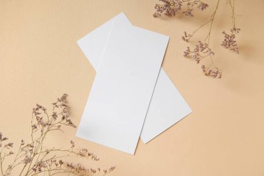Boş kartla kompozisyon ve bej arkaplanda kurumuş çiçekler, yakın plan.
