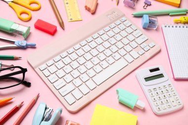 Pembe arka planda bilgisayar klavyesi ve farklı okul malzemeleri, yakın plan
