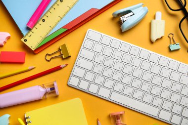 Farklı okul malzemeleri ve turuncu arka planda bilgisayar klavyesi, yakın plan