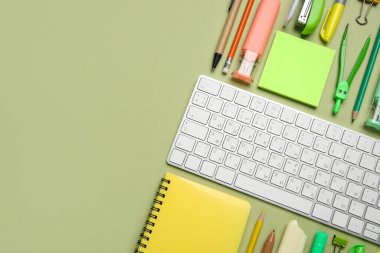 Yeşil arka planda bilgisayar klavyesi ve farklı okul malzemeleriyle kompozisyon, yakın plan