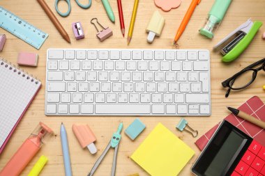 Ahşap arka planda bilgisayar klavyesi, gözlük ve okul malzemeleri ile kompozisyon, yakın plan