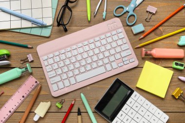 Ahşap arka planda bilgisayar klavyesi, gözlük ve okul malzemeleri ile kompozisyon, yakın plan