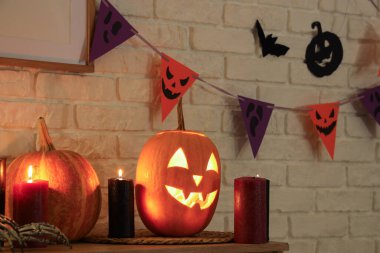 Karanlık odadaki raflarda yanan mumlarla Cadılar Bayramı kabakları