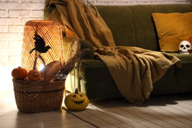 Cadılar Bayramı için dekore edilmiş oturma odasının içi akşamları kanepe, sepet ve parlayan lambayla süslenir.