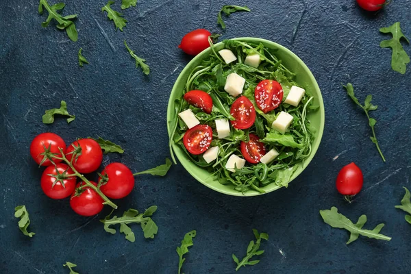 Lezzetli roka salatası ve mavi grunge arkaplanda malzemelerle dolu bir kase.