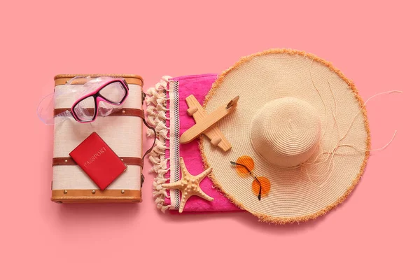 Klasik bavul, pasaport, yüzme maskesi ve pembe arka planda plaj aksesuarları olan kompozisyon