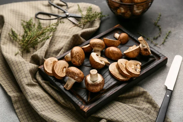 Arka planda çiğ şampiyon mantarlı tahta kesme, yakın plan.
