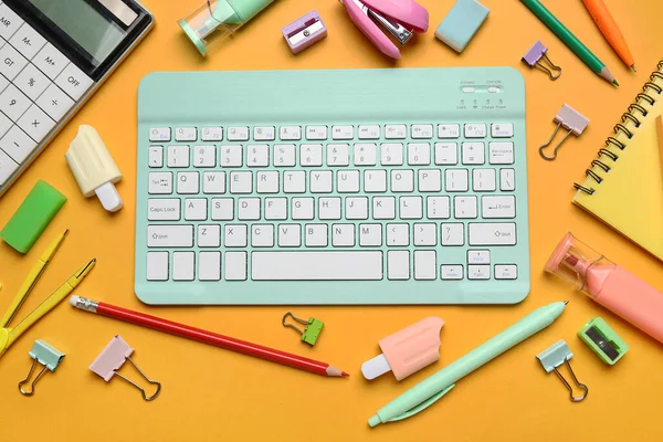 Farklı okul malzemeleri ve turuncu arka planda bilgisayar klavyesi, yakın plan