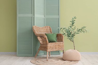 Oturma odasının içi, yeşil katlı ekran, koltuk ve puf