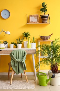 İçinde yeşil bitkiler ve masa olan bir oda.