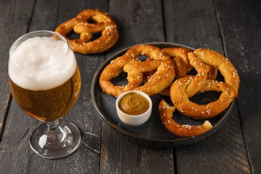 Siyah ahşap arka planda soğuk bira ve simit bardaklarıyla kompozisyon, yakın plan.