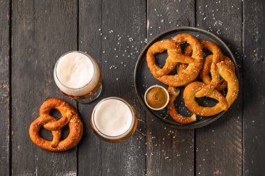 Siyah ahşap arka planda soğuk bira ve simit bardaklarıyla kompozisyon, yakın plan.