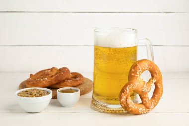 Simitler, soğuk biralı bardak ve beyaz ahşap arka planda hardallı kaseler, yakın plan.