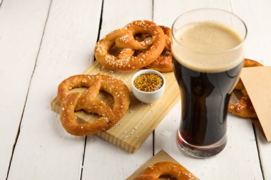 Tahtalı kompozisyon, siyah bira ve beyaz ahşap arka planda krakerler, yakın plan.