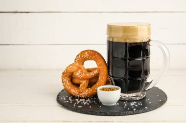 Çubuk kraker, bir fincan koyu bira ve beyaz ahşap arka planda hardallı kase, yakın plan.