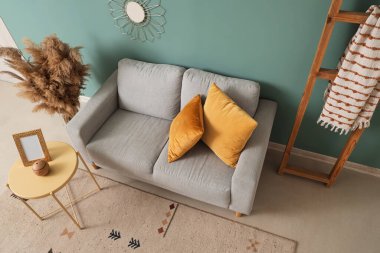 Gri kanepe, masa ve merdiven manzaralı şık bir oturma odası.