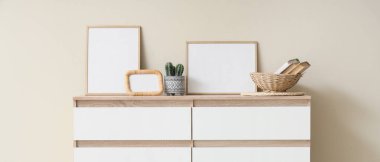 Çerçeveli çekmeceler ve bej duvarın yanında dekorasyon odası