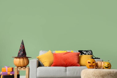 İçinde kanepe, Cadılar Bayramı balkabağı ve hediyeler olan bir oturma odası.