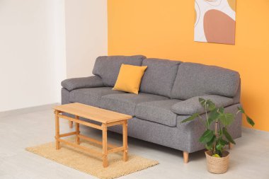 Rahat kanepesi, sehpası ve turuncu duvarın yanındaki çiçekli şık oturma odasının içinde.