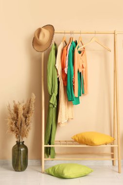 Modern soyunma odasının içinde vazoda otlar ve askılar var.