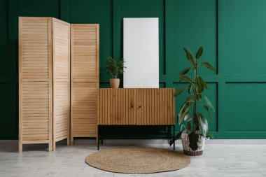 Ev bitkileriyle klozet, katlanan ekran ve odada yeşil duvarın yanında boş poster