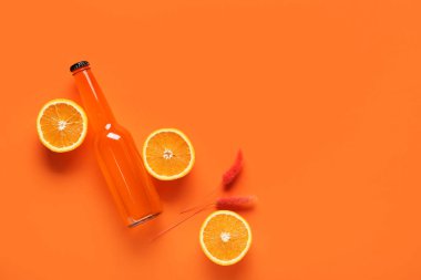 Bir şişe soda ve turuncu arka planda narenciye.