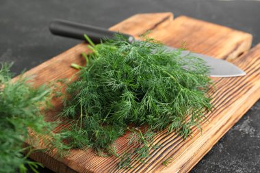 Siyah arka planda taze yeşil dereotu olan ahşap tahta, yakın plan.