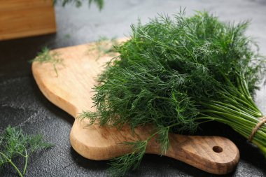 Siyah arka planda taze yeşil dereotlu ahşap tahta, yakın plan.