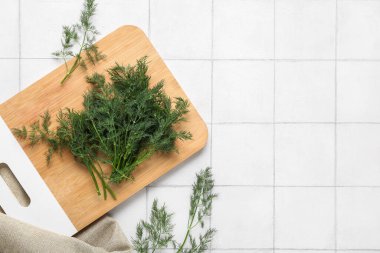 Beyaz fayans zemininde taze yeşil dereotu olan kesme tahtası