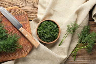 Tahta arka planda taze yeşil dereotlu kase ve kesim tahtası