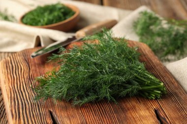 Tahta kesme tahtası ahşap arka planda taze yeşil dereotu, yakın plan