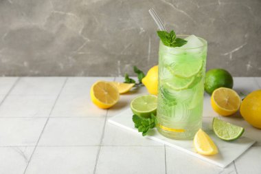 Bir bardak lezzetli soğuk kokteyl ve turunçgil meyveleri beyaz fayans masasında, yakın plan.