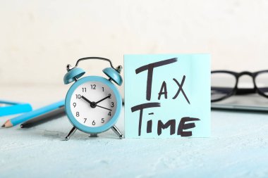 Alarmlı gözlük, kırtasiye ve mesaj saati beyaz duvarın yanındaki grunge mavi masada.