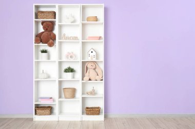 Oyuncak dolu kitaplık ve leylak duvarın yanında bitkiler