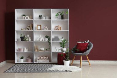 Büyük kitaplığı, bitkileri ve koltuğu olan şık bir oda.