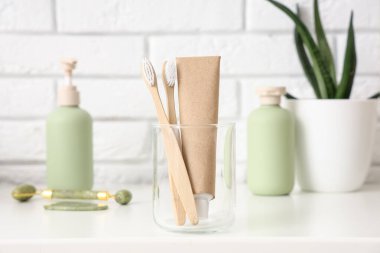 Banyodaki masanın üzerinde diş fırçası olan cam bardak, yakın plan.