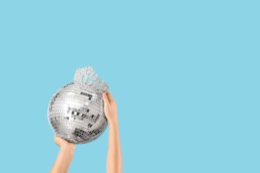 Mavi arka planda disko topu ve tacı olan kadın elleri