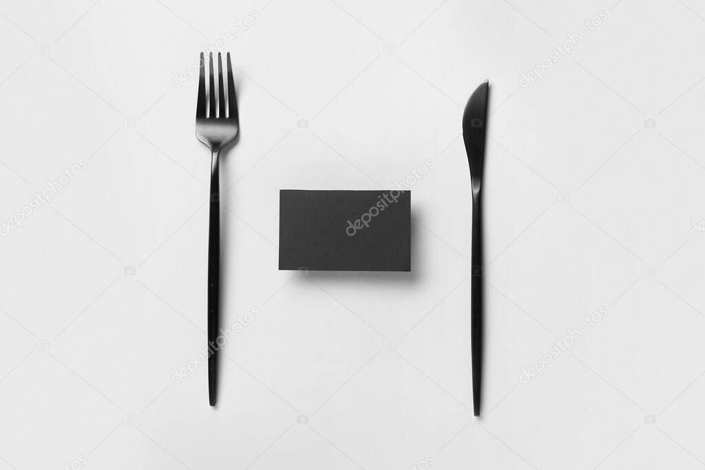 Black blank business card with cutlery on grey background