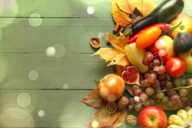 Farklı taze sebzeler, meyveler ve yeşil ahşap arka planda sonbahar yaprakları olan bir pano. Hasat festivali