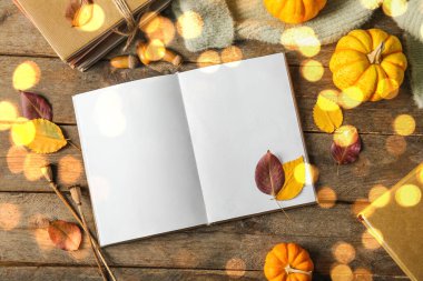 Ahşap arka planda boş kitap, balkabağı ve düşmüş yapraklarla kompozisyon